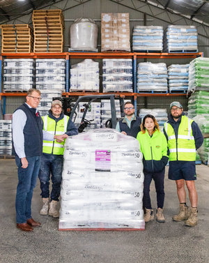 Brendan from CoBright and 4 Austasia Animal Products team members stand around a stacked pellet of ZinMet 50 feed bags. They are in a large warehouse with stacked shelves of Austasia animal feel.