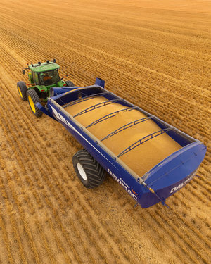 Tractor and grain bin driving through recently harvested paddock