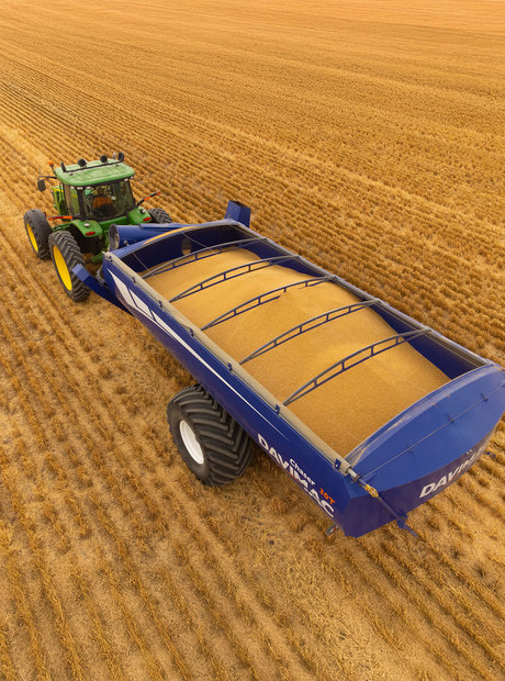 Tractor and grain bin driving through recently harvested paddock