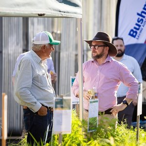 Two men are talking outside of a popup stall tent.